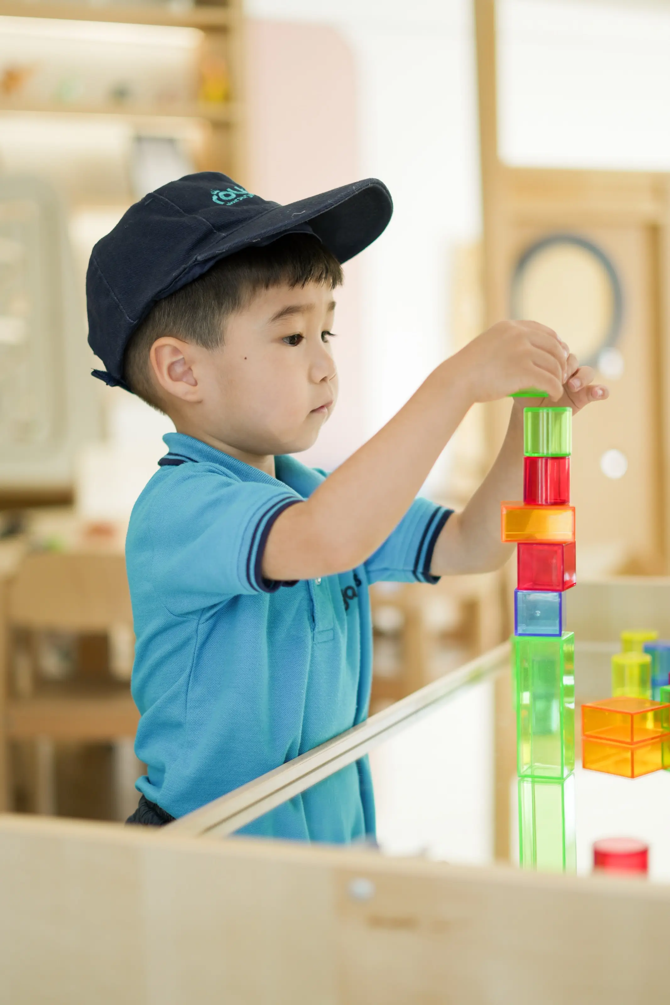 A child balancing translucent coloured cubes on a light table
